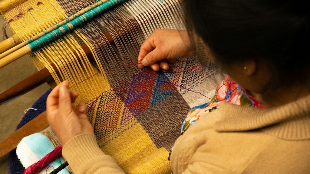Una persona indígena que confecciona ropa